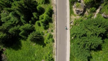 Yukarıdan drone videosu, bir kadın bisikletçiyi takip ediyor. Dişi bisikletçi dağların arasında at sürüyor. Ormanda bisiklet süren bir kadın. Sağlıklı bisiklet yaşam tarzı. Bucegi Dağları, Romanya