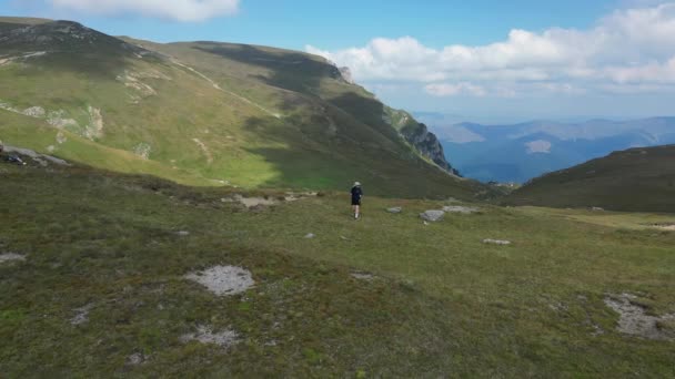 夏の晴れた日の山頂を歩く女性観光客の空想的な景色 女性観光客は山の丘の間をハイキングしています 観光客は領土を探索しています ブクジル自然公園 ルーマニア — ストック動画