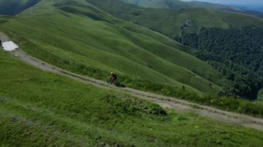 Toprak dağ yolunda dağ bisikleti süren adamların hava görüntüleri. Dağların güzel manzarası. Bisikletçileri takip et..