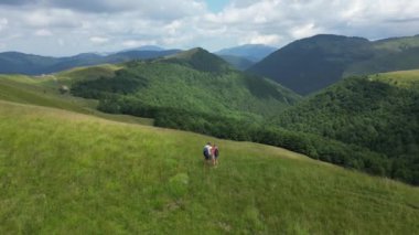 Karpat Dağları 'nda durmuş manzaranın tadını çıkaran mutlu bir çift. Seyahat kavramı. Sırt çantalı gezginler tatilin tadını çıkarırlar. Turist seyahati doğanın tadını çıkarıyor
