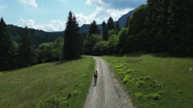 Hava aracı görüntüsü profesyonel bisikletçinin yoğun çakıllı bisikleti dağ yolunda tırmanıyor. Güneşli bir yaz gününde doğada bisiklete biniyor. Çakıl bisikleti macerası. Çakıl yolundaki dağlarda bisiklet eğitimi..