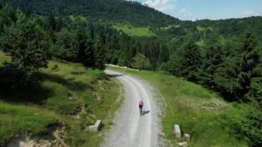 Çakıl yolunda bisiklet süren bir kız. Çakıl bisikleti üzerinde bisiklet. Kadın sporu ve seyahat. Açık hava maceraları..