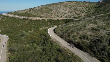 Üç bisikletçi İspanya 'da Vall d' Ebo geçidini fethetti. Bisikletçiler dağlarda bisiklet eğitimi aldılar. Dağa doğru pedal çevirdiler. Üç sporcu Vall de Ebo geçişlerinde eğitim görüyor.Drone video 4k