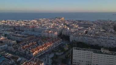Sakin İspanyol şehrinin arka planında deniz bulunan yerleşim alanının hava görüntüleri. Gün batımı zamanı. İnsansız hava aracı görüntüleri. Tatil yeri. Kuş bakışı şehir. Torrevieja, İspanya