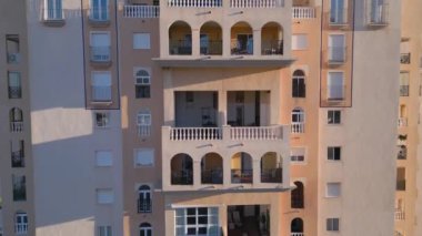 Kamera renkli yüksek binalardan uzaklaşarak deniz kıyısı ve apartmanlı bloğu gösteriyor. Emlak satışı videosu. Torrevieja, İspanya