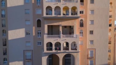Kamera renkli yüksek binalardan uzaklaşarak deniz kıyısı ve apartmanlı bloğu gösteriyor. Emlak satışı videosu. Torrevieja, İspanya