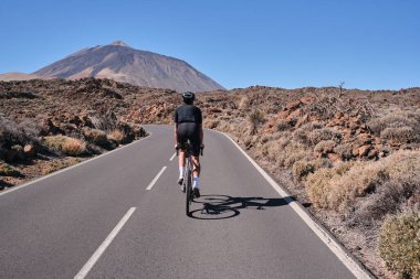 Erkek bisikletçi, Tenerife, Kanarya Adaları, İspanya 'daki Teide volkanı manzaralı yolda pedal çeviriyor. Sporcu dışarıda bisiklet eğitimi alıyor. Liman motivasyonu. Açık havada bisiklet eğitimi. Hippi bisikletçi..