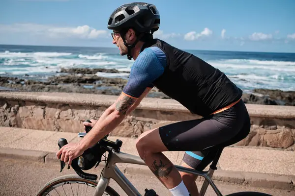 Bisikletçi adam çakıl bisikleti sürüyor. Tenerife, Kanarya Adaları, İspanya 'da Atlantik Okyanusu manzaralı çakıl yolu. Spor motivasyonu. İspanya 'da bisiklet eğitimi. Bisiklet macerası.