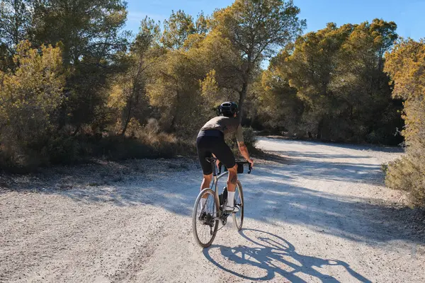 Cyclist practicing on gravel road. Fit male cyclist riding a gravel bike on a gravel road, Alicante region of Spain. Beautiful sunny day for cycling. Motivation image of an athlete.