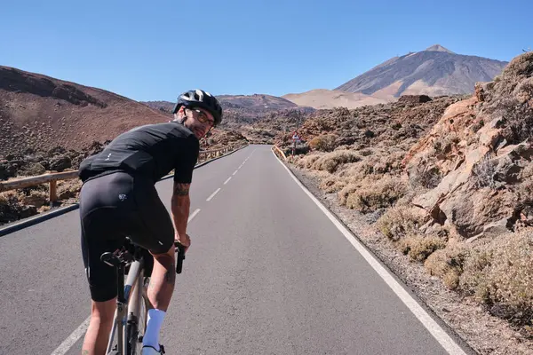Erkek bisikletçi, Tenerife, Kanarya Adaları, İspanya 'daki Teide volkanı manzaralı yolda pedal çeviriyor. Sporcu dışarıda bisiklet eğitimi alıyor. Liman motivasyonu. Açık havada bisiklet eğitimi. Hippi bisikletçi..