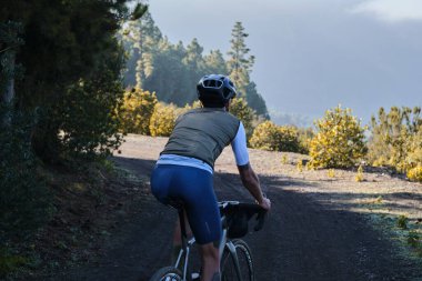 Çakıl yolunda çalışan bir bisikletçi. Taş yolda çakıl bisikleti süren formda bir bisikletçi. İspanya 'nın Tenerife Adası' ndaki dağları görüyor.