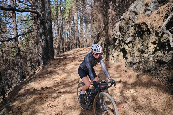 Çakıl yolu üzerinde bisiklet ve kaskla bisiklet süren genç bir kadın bisikletçi. Güzel dağ yollarında bisiklet macerası. Tatil sırasında kırsalda bisiklet süren bir sporcu. İspanya