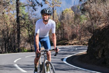 Erkek bisikletçi asfalt yolda Tenerife, Kanarya Adaları, İspanya 'daki yanmış ormandan geçiyor. Spor motivasyonu. İspanya 'da bisiklet eğitimi. Bisiklet macerası. Sporcu bisikletle sıkı çalışıyor.