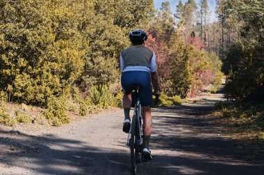 Arka planda, Tenerife, Kanarya Adaları 'ndaki ormanda çakıllı bisiklet süren erkek bisikletçinin görüntüsü var. Spor motivasyonu. İspanya 'da bisiklet eğitimi. Bisiklet macerası .