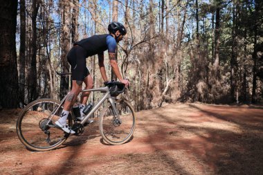 Erkek sporcu boş yolda zaman bisikleti sürüyor. Hedeflerine odaklanmış: Motivasyonlu Erkek Triatlet Her şeyini bisiklet sahnesinde veren yeşil formalı ve beyaz kasklı bir adamın resmi.