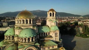 Bulgaristan 'ın Sofya kentindeki St. Alexander Nevsky Katedrali' nin insansız hava aracı görüntüsü. Güneş doğarken yeşil ağaçlarla çevrili ikonik Bulgar ortodoks kilisesinin görüntüleri.