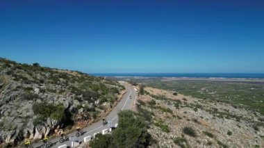 Dönemeç yolundaki tepeden inen grup bisikletçilerinin hava aracı görüntüleri. Bisiklet ve triatlon konsepti. Sporcular bisikletle antrenman yapıyor. La Vall d 'Ebo, Alicante, İspanya