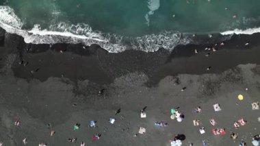 Kanarya Adaları 'ndaki Puerto de la Cruz' daki merkez plajın hava manzarası. Jardin plajında uçan insansız hava aracı. Palmiyeleri ve mavi suları olan güzel siyah volkanik kumsal..