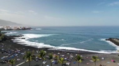 Kanarya Adaları 'ndaki Puerto de la Cruz' daki merkez plajın hava manzarası. Jardin plajında uçan insansız hava aracı. Palmiyeleri ve mavi suları olan güzel siyah volkanik kumsal..