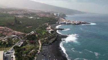 Kanarya Adaları 'ndaki Puerto de la Cruz' daki merkez plajın hava manzarası. Jardin plajında uçan insansız hava aracı. Palmiyeleri ve mavi suları olan güzel siyah volkanik kumsal..