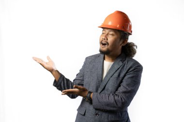 Bir patronun mutlu ifadesi. Beyaz arka planda turuncu kasklı takım elbiseli şık Asyalı bir adam. inşaat ya da madencilik konsepti fotomontaj ya da madencilik iş konsepti fotoğrafı