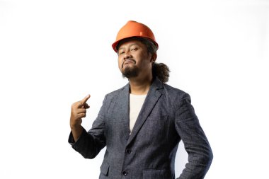 Proje lideri orta parmağıyla hareket eder. Beyaz arka planda turuncu takım elbiseli ve kasklı şık Asyalı bir adam. inşaat ya da madencilik konsepti fotoğrafı