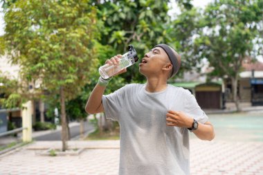 Kel bir Asyalı sabah elinde içki kadehiyle koşarken kendinden emin ve mutlu görünür..