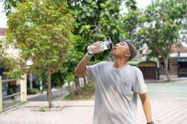 Kel bir Asyalı sabah elinde içki kadehiyle koşarken kendinden emin ve mutlu görünür..