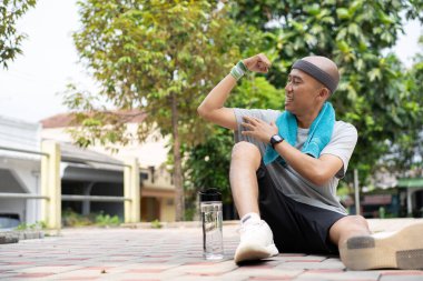 Kel bir Asyalı sabah elinde içki kadehiyle koşarken kendinden emin ve mutlu görünür..