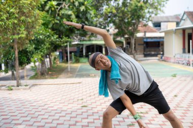 Endonezyalı Asyalı adam sabah koşusundan önce ısınıyor. Sağlıklı yaşam tarzı kavramı.
