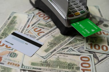Kredi kartı ve EDC makinesi 100 dolarlık banknotların üzerinde, para birimi kavramı.