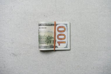 Gri arka planda izole edilmiş, lastik bantlarla bağlanmış 100 dolarlık banknotlar..