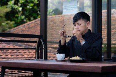 Genç bir adam açık kahve dükkanında ya da kafede kahve içiyor.