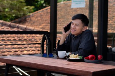 Genç bir adam açık kahve dükkanında ya da kafede kahve içiyor.