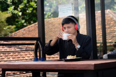 Genç bir adam açık kahve dükkanında ya da kafede kahve içiyor.