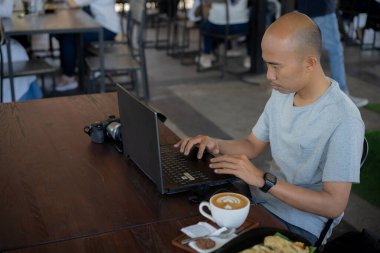 Yarı açık kafede çalışan dizüstü bilgisayarlı ciddi bir adam.