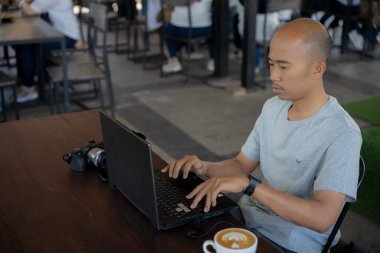 Yarı açık kafede çalışan dizüstü bilgisayarlı ciddi bir adam.