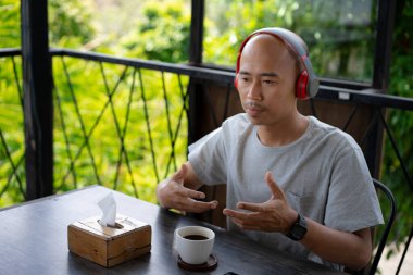 Kel bir Asyalı çocuk, bir kafede takılırken telefonundan bir video mesajı aldığında mutlu görünüyor..