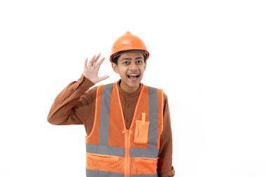 Tam güvenlik kıyafetli Endonezyalı genç erkek inşaat işçisi beyaz arka planda izole edilmiş kamera, inşaat ve endüstri konseptine güvenle bakıyor..