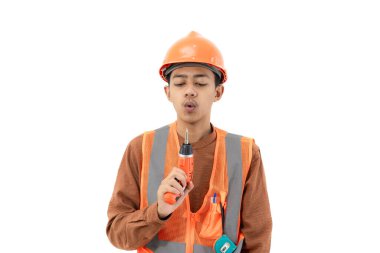 Genç Endonezyalı erkek inşaat işçisi, beyaz arka planda izole edilmiş, matkap, inşaat ve endüstri konseptini kullanarak tam güvenlik donanımı ile poz veriyor..