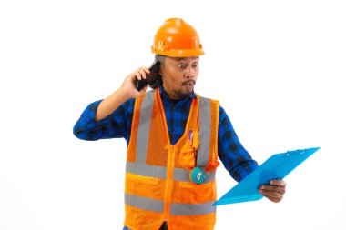 Endonezyalı erkek inşaat işçisi, beyaz arka planda izole edilmiş, pano, inşaat ve endüstri kavramını elinde tutarken ses çağrısı yaparak güvenlik ekipmanı kullanıyor..