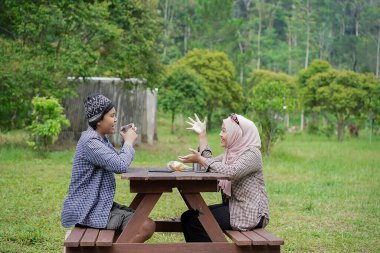 Endonezyalı genç erkek ve kadınlar sakin doğal atmosferin ve seyahat konseptinin tadını çıkarırken piknik yapıyorlar..