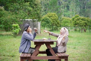 Endonezyalı genç erkek ve kadınlar sakin doğal atmosferin ve seyahat konseptinin tadını çıkarırken piknik yapıyorlar..