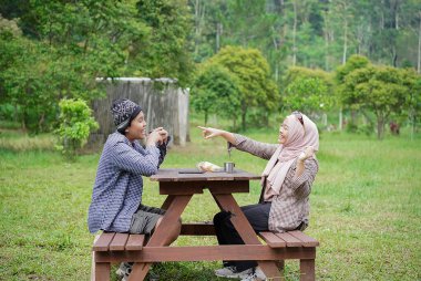 Endonezyalı genç erkek ve kadınlar sakin doğal atmosferin ve seyahat konseptinin tadını çıkarırken piknik yapıyorlar..
