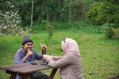 Endonezyalı genç erkek ve kadınlar sakin doğal atmosferin ve seyahat konseptinin tadını çıkarırken piknik yapıyorlar..