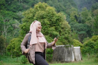 Endonezyalı genç kadın gezgin tesettür takıyor doğada seyahat ederken yön arıyor, seyahat kavramı.