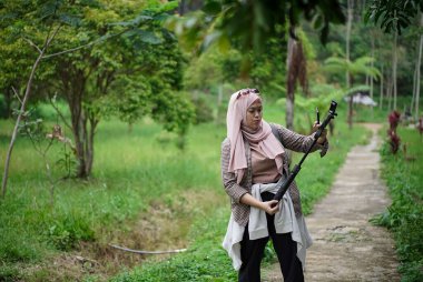 Endonezyalı genç bir adam, Endonezyalı genç bir kadının doğada yürürken ve seyahat konseptinde video kayıt cihazları hazırlamasına yardım ediyor..