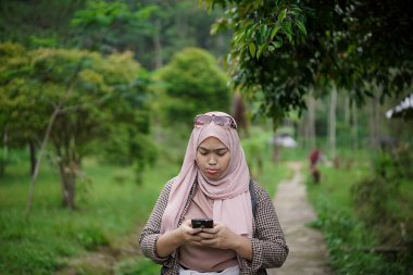 Kafası karışık genç Endonezyalı kadın doğada yürürken yön arıyor, seyahat konsepti.