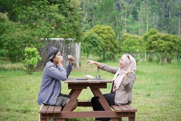 Endonezyalı genç erkek ve kadınlar sakin doğal atmosferin ve seyahat konseptinin tadını çıkarırken piknik yapıyorlar..
