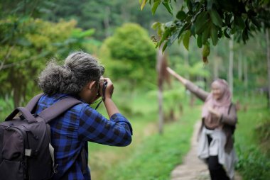 Profesyonel fotoğrafçı, Endonezyalı genç bir kadın modelin başörtüsü içinde fotoğraf çekiyor. Doğada seyahat ederken poz veriyor. Seyahat kavramı..
